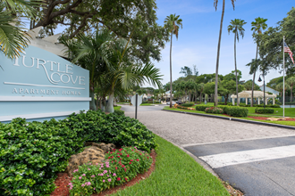 the entrance to turtle cove apartments with palm trees and a sign