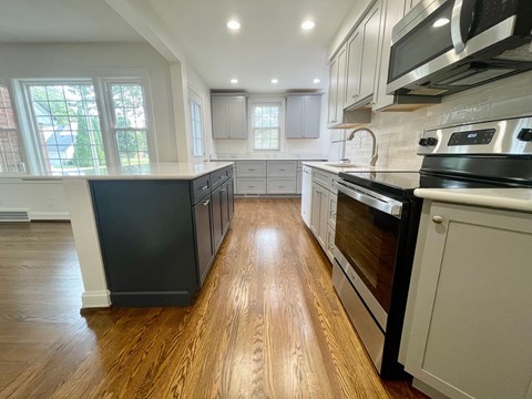 A kitchen with black appliances and wooden floors.
