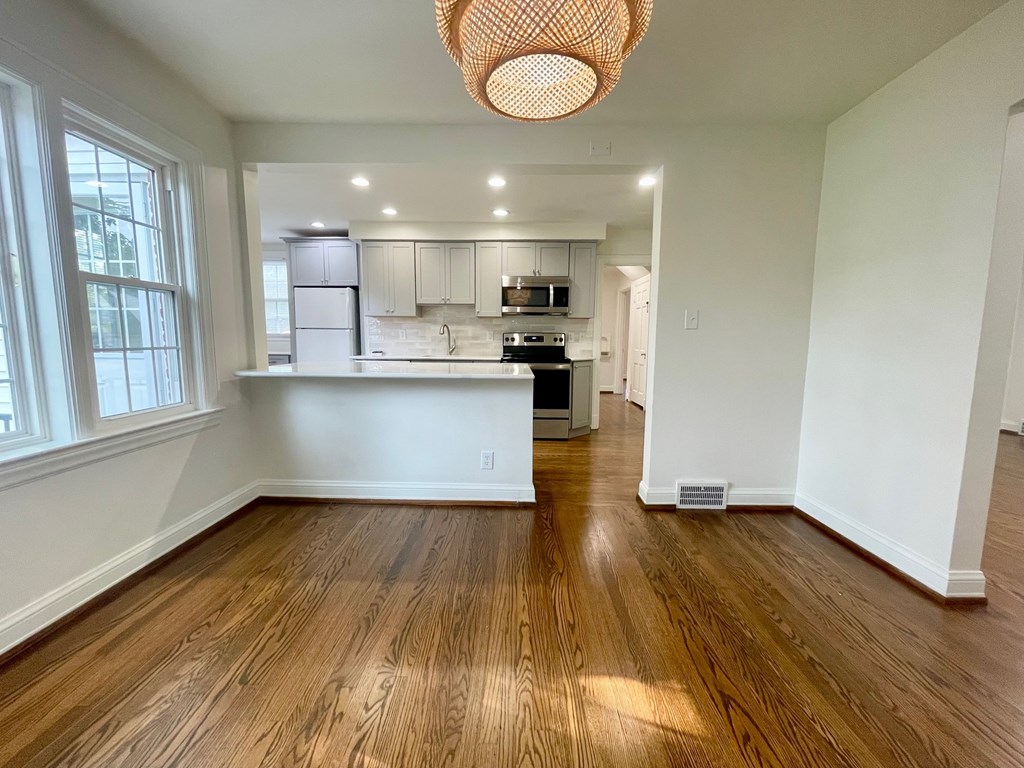 A kitchen with wooden floors and a hanging light fixture.