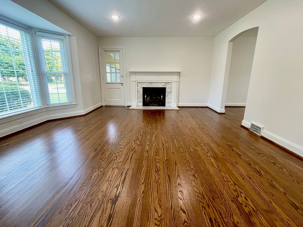 A room with a fireplace and wood flooring.