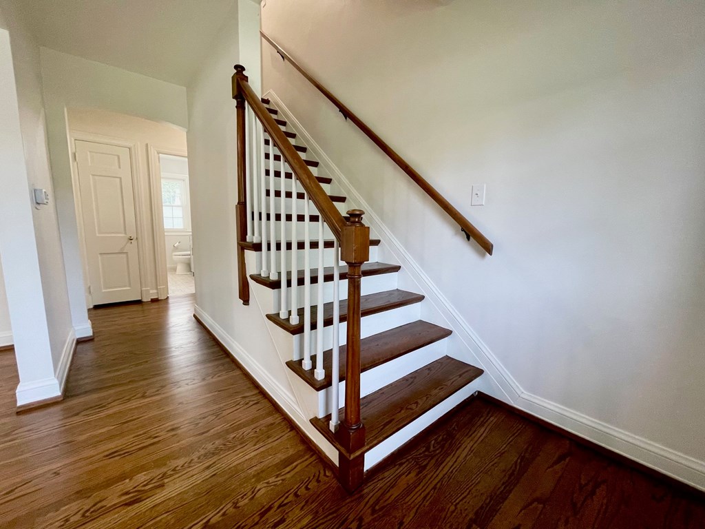 A wooden staircase with white railings leads up to a white door.