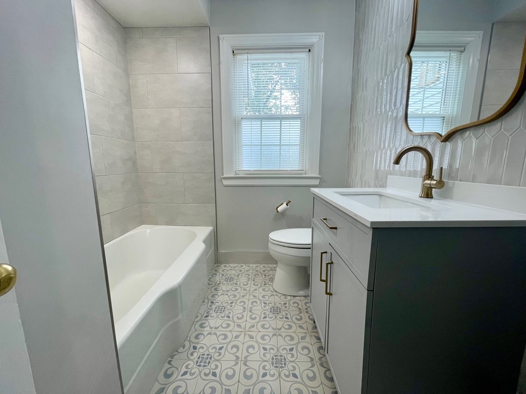 A bathroom with a white tub, toilet, and sink.