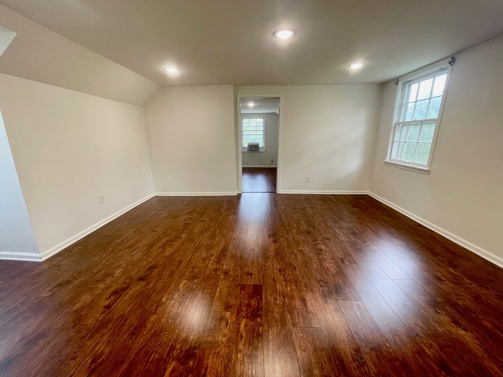 A room with wooden flooring and a window on the right side.