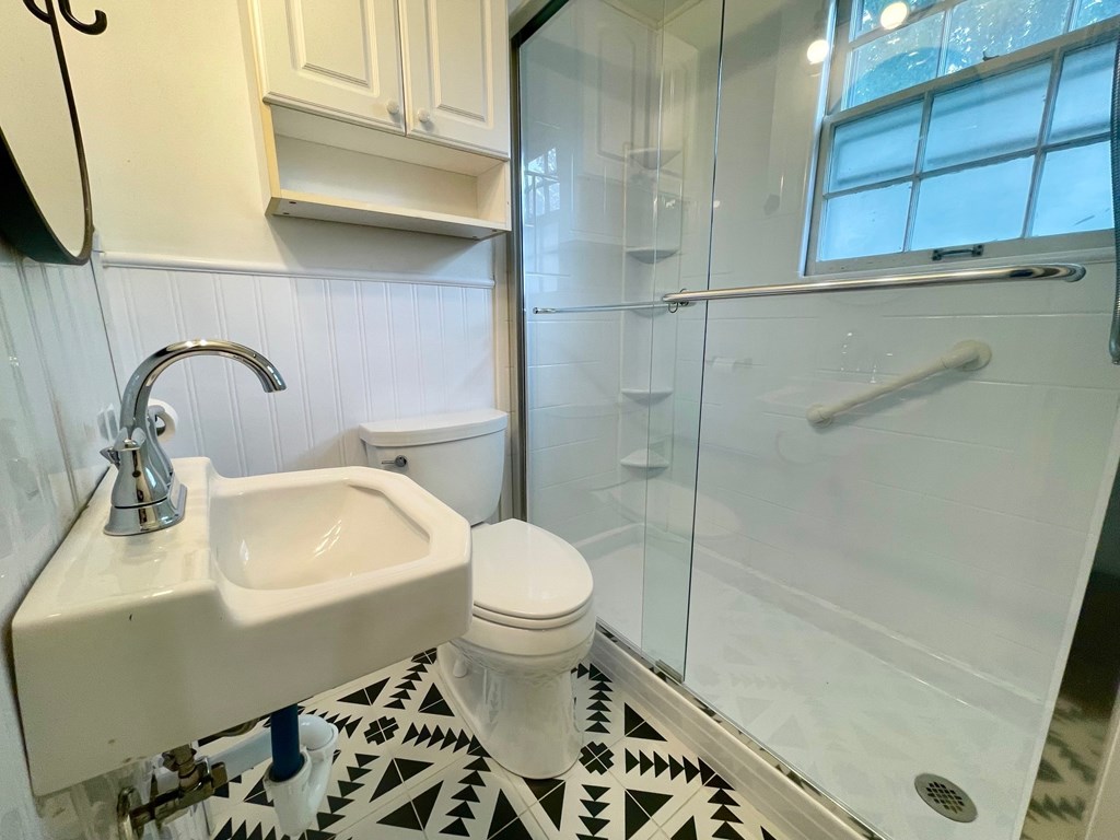 A white sink and toilet in a bathroom with a black and white tiled floor.