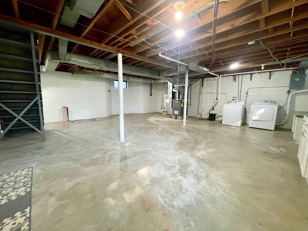 A large, empty room with a concrete floor and a staircase on the left side.