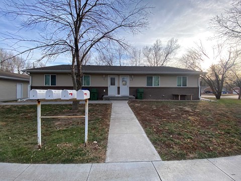 the front of a house with mailboxes on the sidewalk