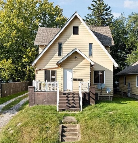 A small house with a porch and a satellite dish on the roof.