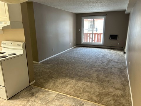 a kitchen and an empty living room with a stove and a window