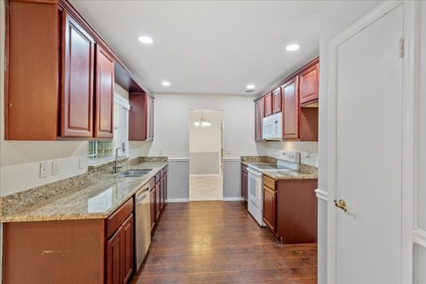 A kitchen with brown cabinets and a granite countertop.