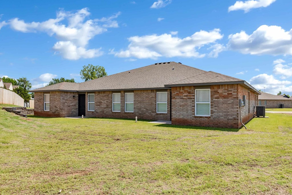a brick house with a grassy yard and a cloudy sky