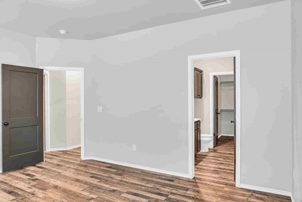 a room with a door and a hallway with a wood floor