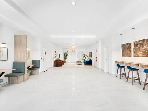 A long, white hallway with blue chairs and wooden furniture.