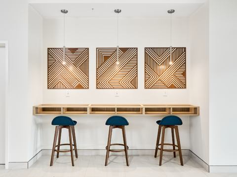 A bar with three stools and three hanging lights.