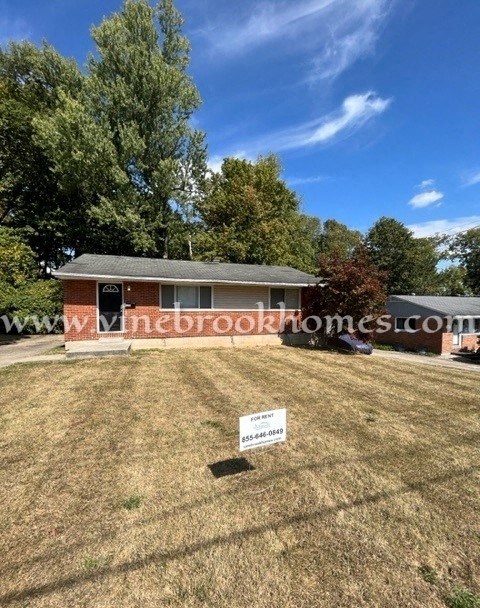 a small brick house with a yard and a sign in front of it