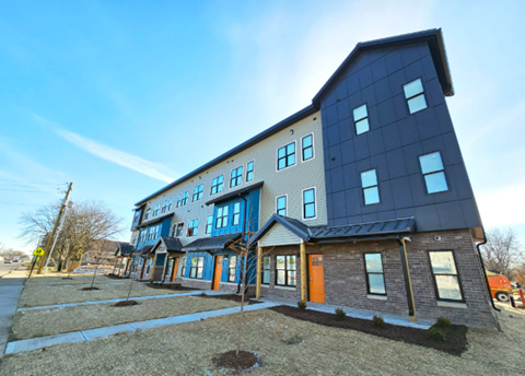 A modern two-story building with a blue exterior and a red door.
