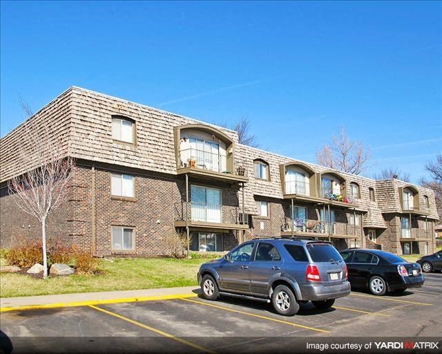 an apartment building with cars parked in a parking lot