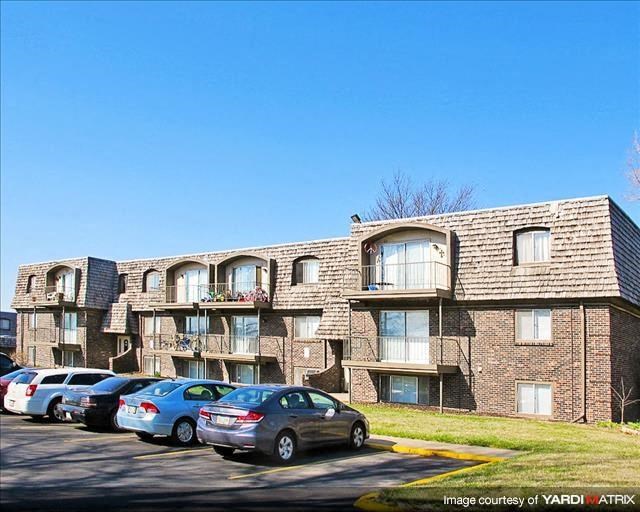 a brick apartment building with cars parked in a parking lot