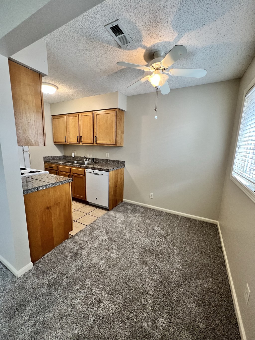 an empty kitchen with a ceiling fan and