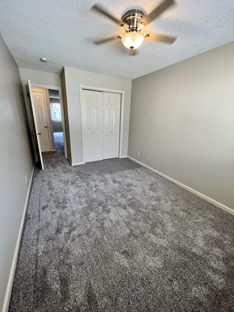 an empty living room with carpet and a ceiling fan