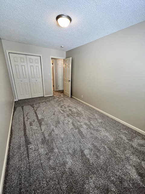 an empty living room with carpet and a door to a hallway