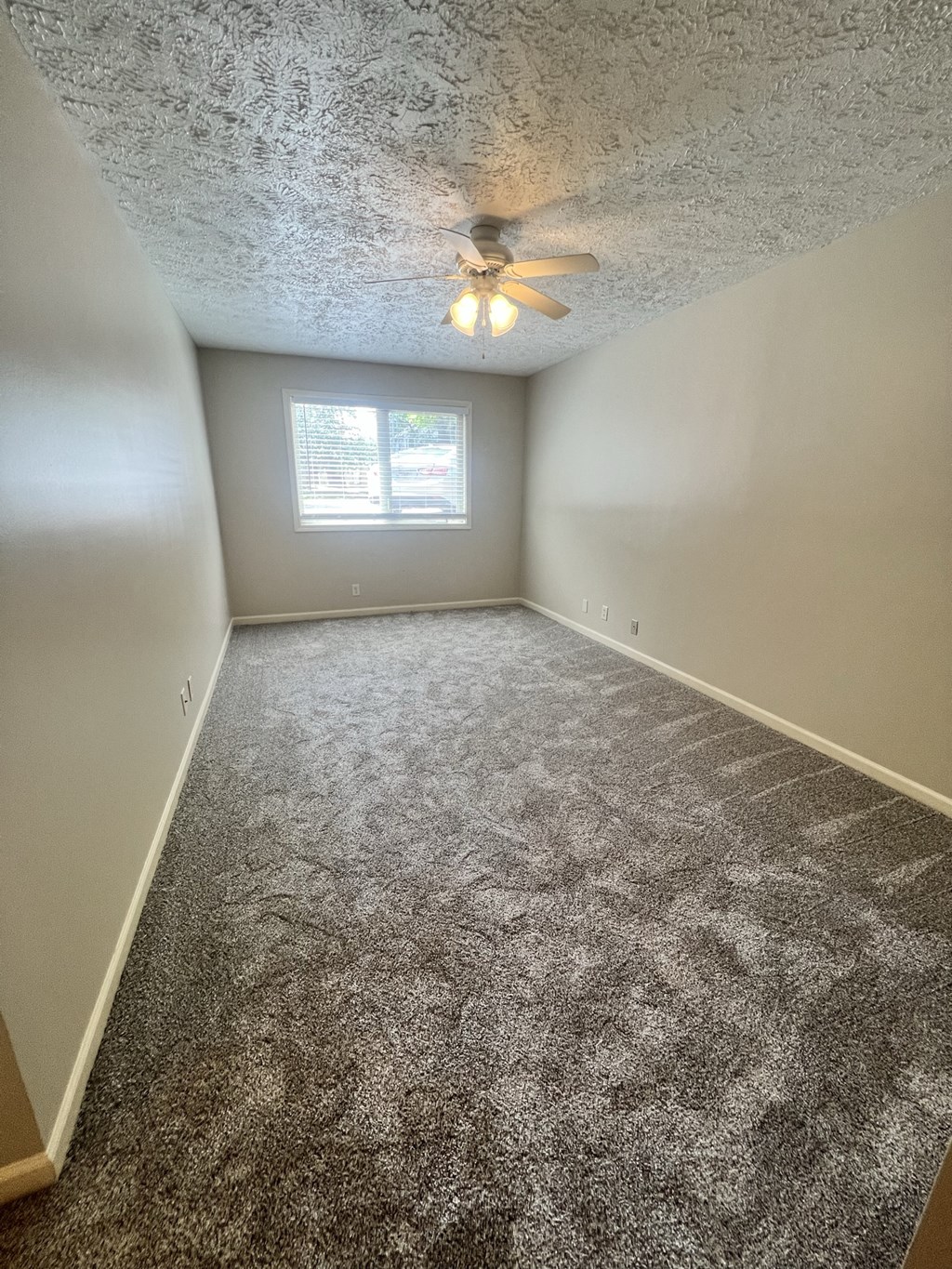 an empty bedroom with carpet and a ceiling fan