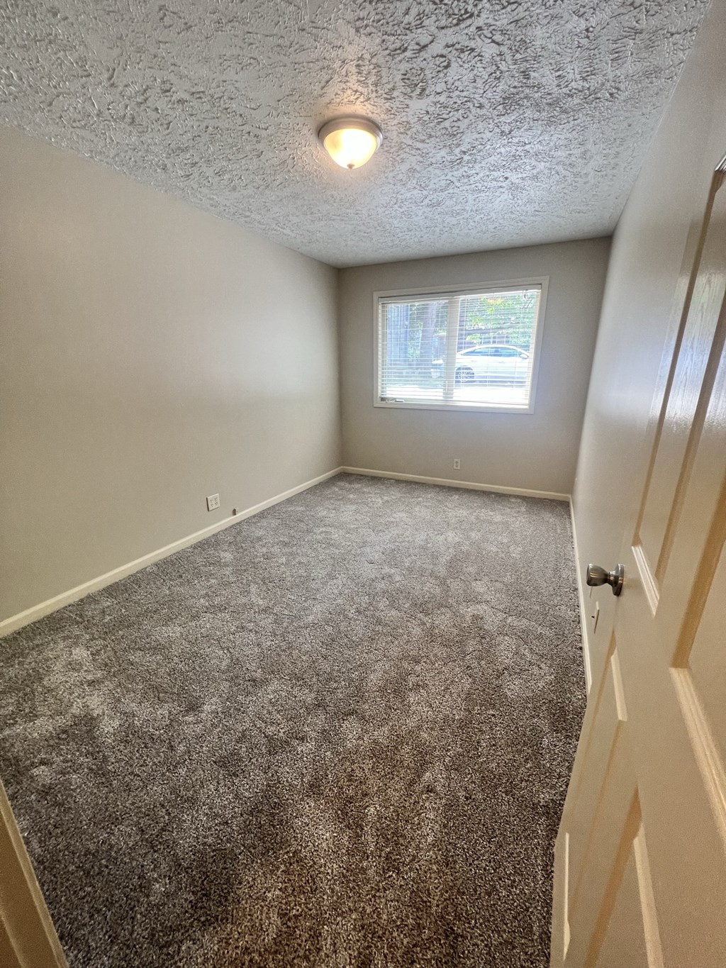 an empty bedroom with carpet and a window