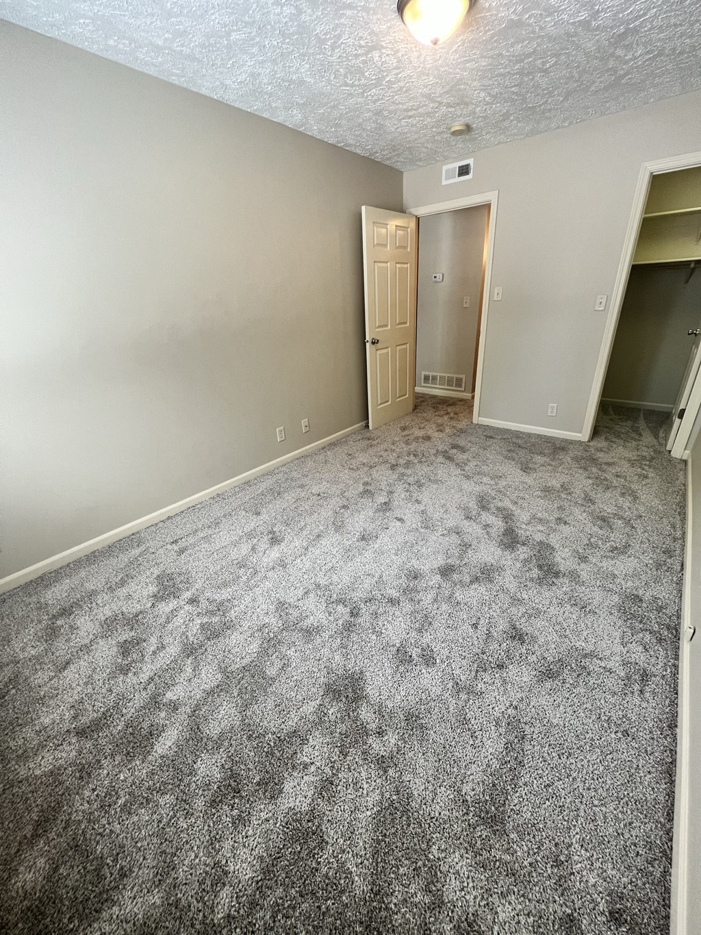 an empty living room with gray carpet and a door to a closet
