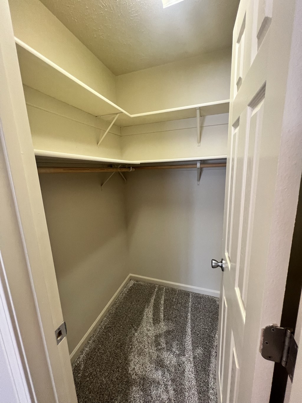 a walk in closet in an empty room with a white door