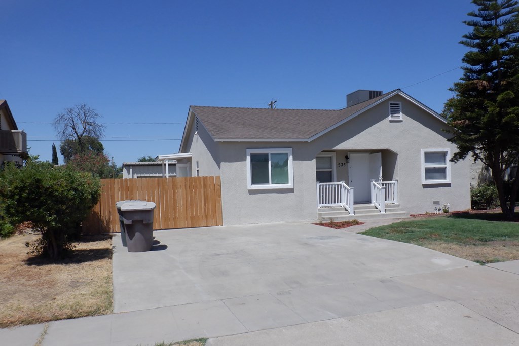 a white house with a driveway and a wooden fence