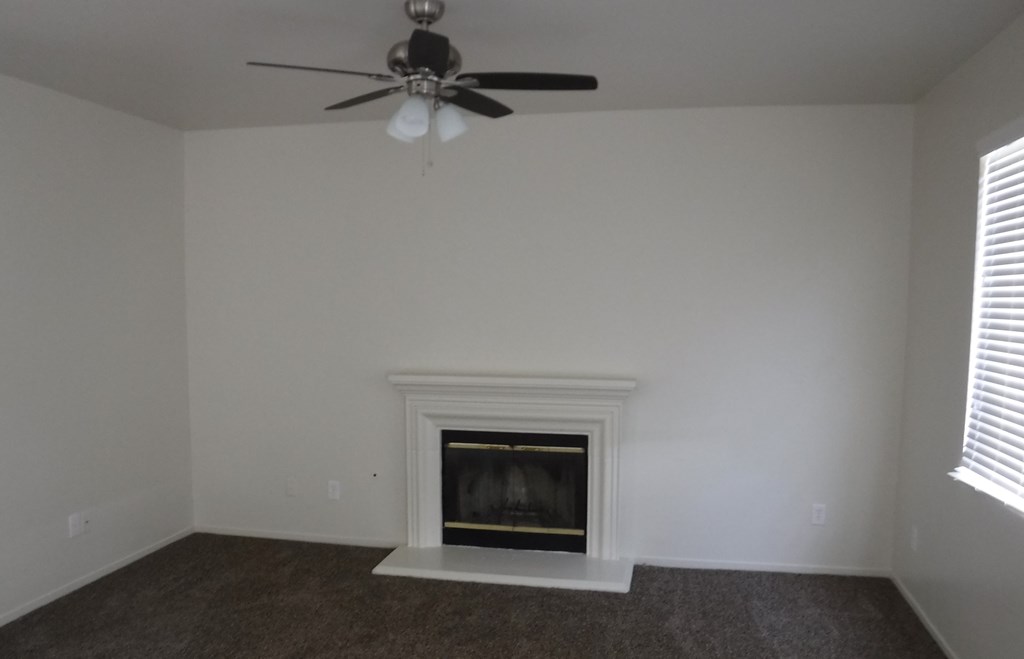 a living room with a fireplace and a ceiling fan