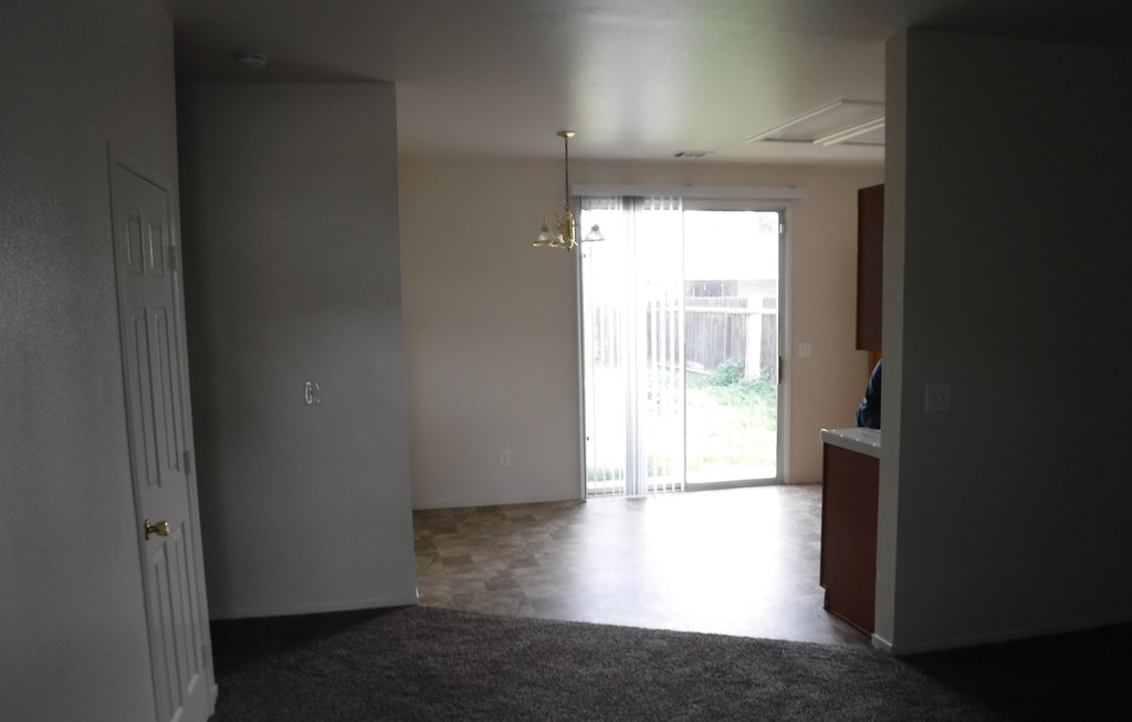 an empty living room with a sliding glass door to a patio