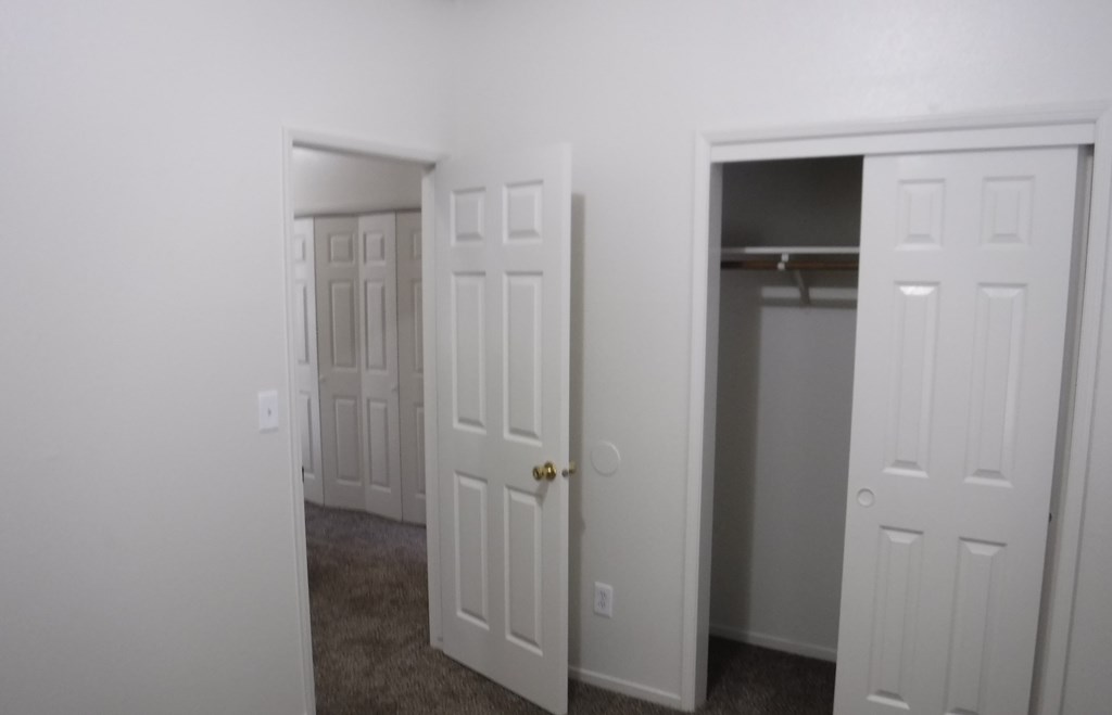 an empty bedroom with three doors and a closet