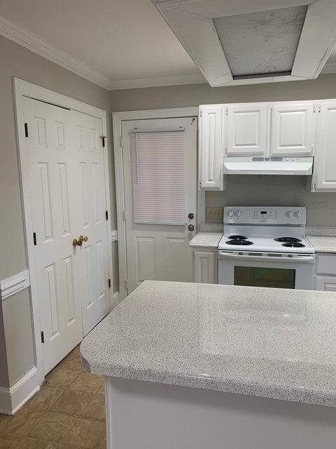 A kitchen with white cabinets and a granite countertop.