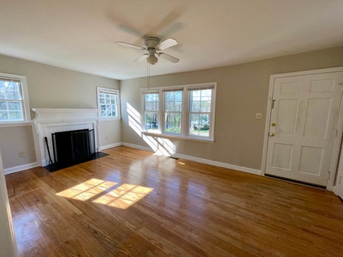 an empty living room with a fireplace and a ceiling fan