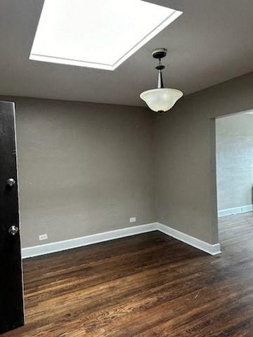 an empty room with wood floors and a ceiling light