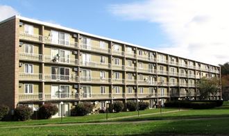 a large apartment building with balconies and a lawn in front