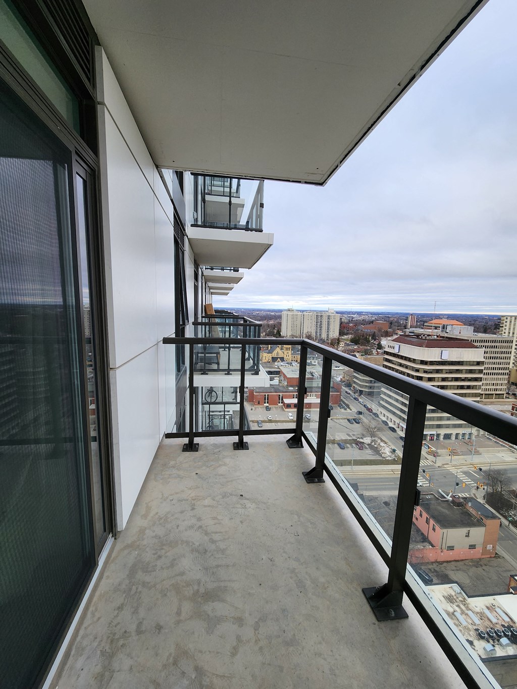 a balcony with a view of a city and a balcony railing and a glass door