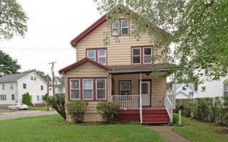 a yellow house with a red porch and a tree