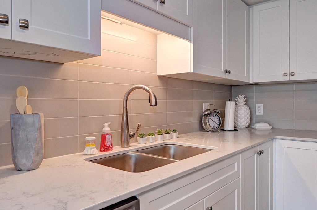 a white kitchen with a sink and white cabinets