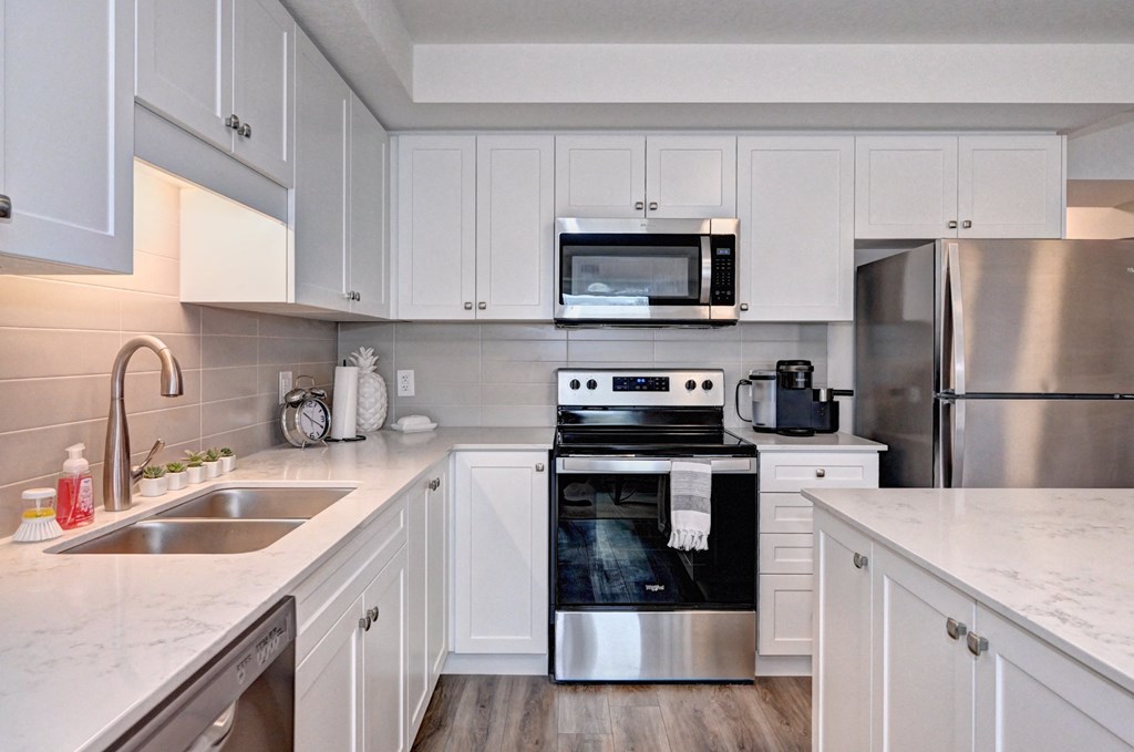 a white kitchen with stainless steel appliances and white cabinets