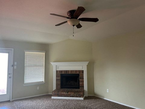 a living room with a fireplace and a ceiling fan