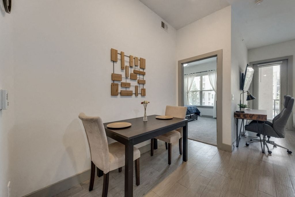 a dining area with a table and chairs and a door to a living room