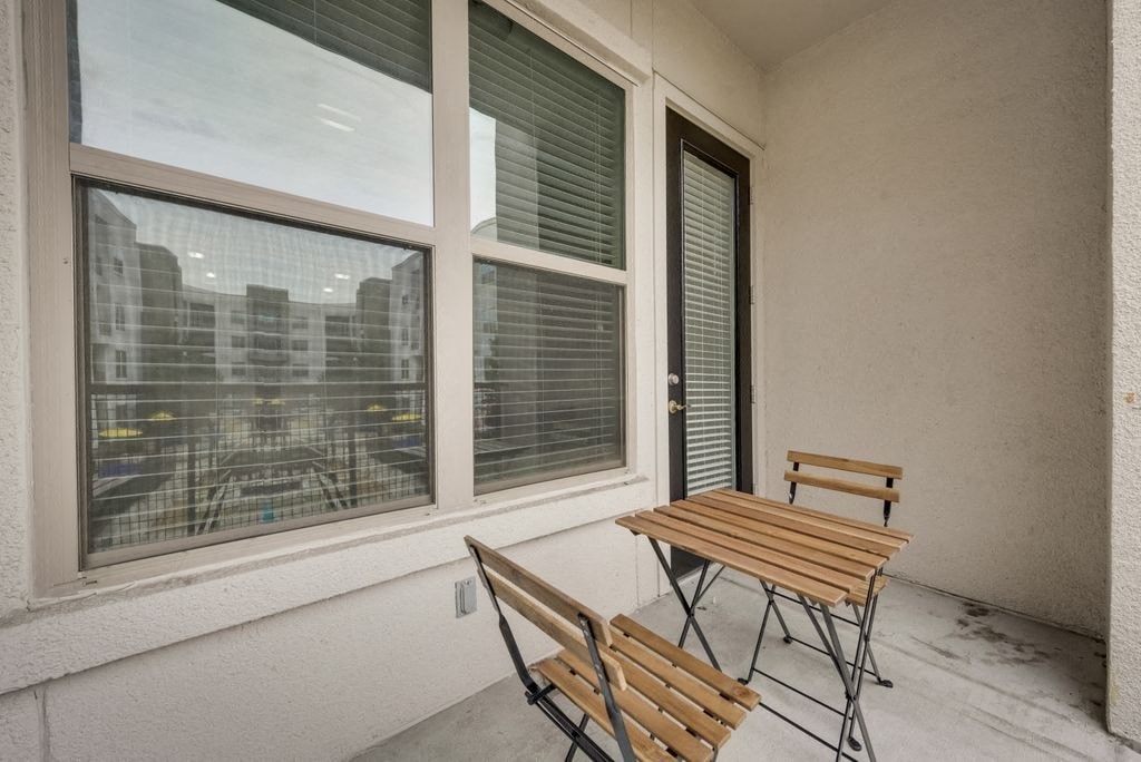 a balcony with a table and two chairs and two large windows