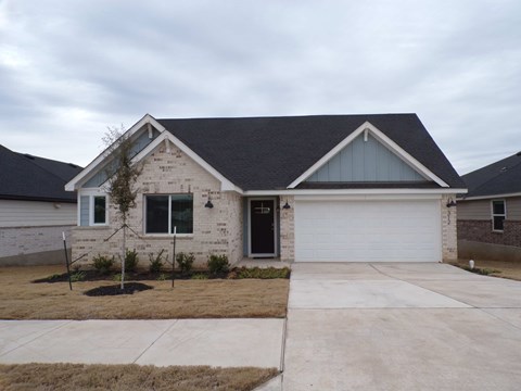 a white brick house with a gray roof and a driveway