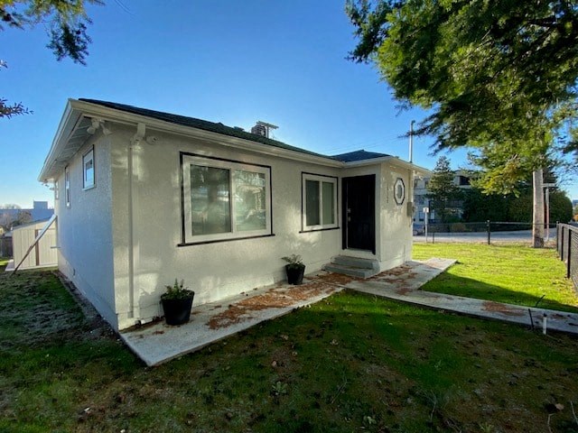 a small gray house with a yard and a tree