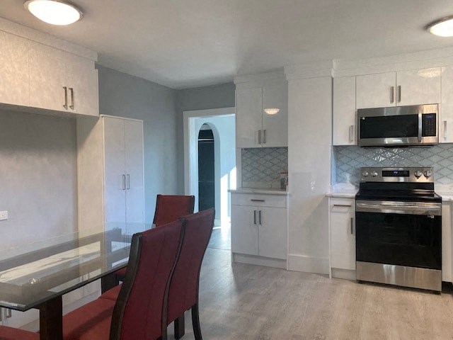 a kitchen with white cabinets and a table and chairs
