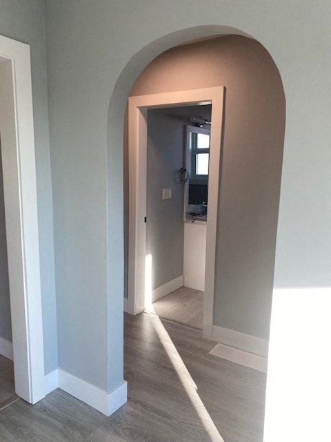 a hallway with an arched doorway and a door to a bathroom
