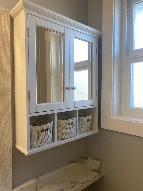 a bathroom with a cabinet with baskets and a window