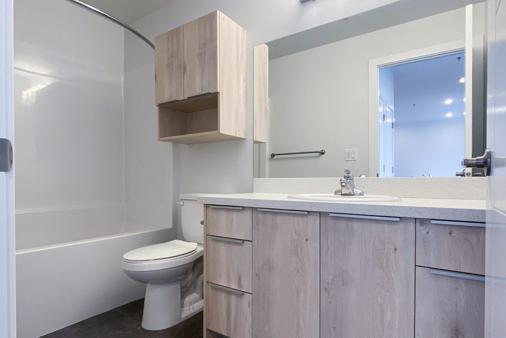 A white toilet sits in a bathroom with a wooden cabinet above it.