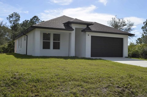 a white house with a garage and a lawn